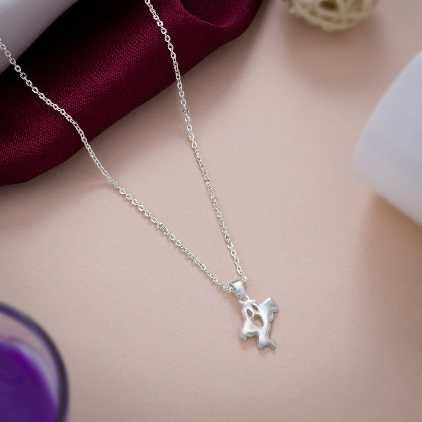 silver necklace with a small ghost  on it