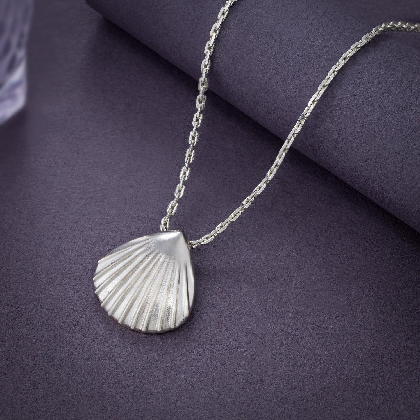 silver necklace with a shell on it