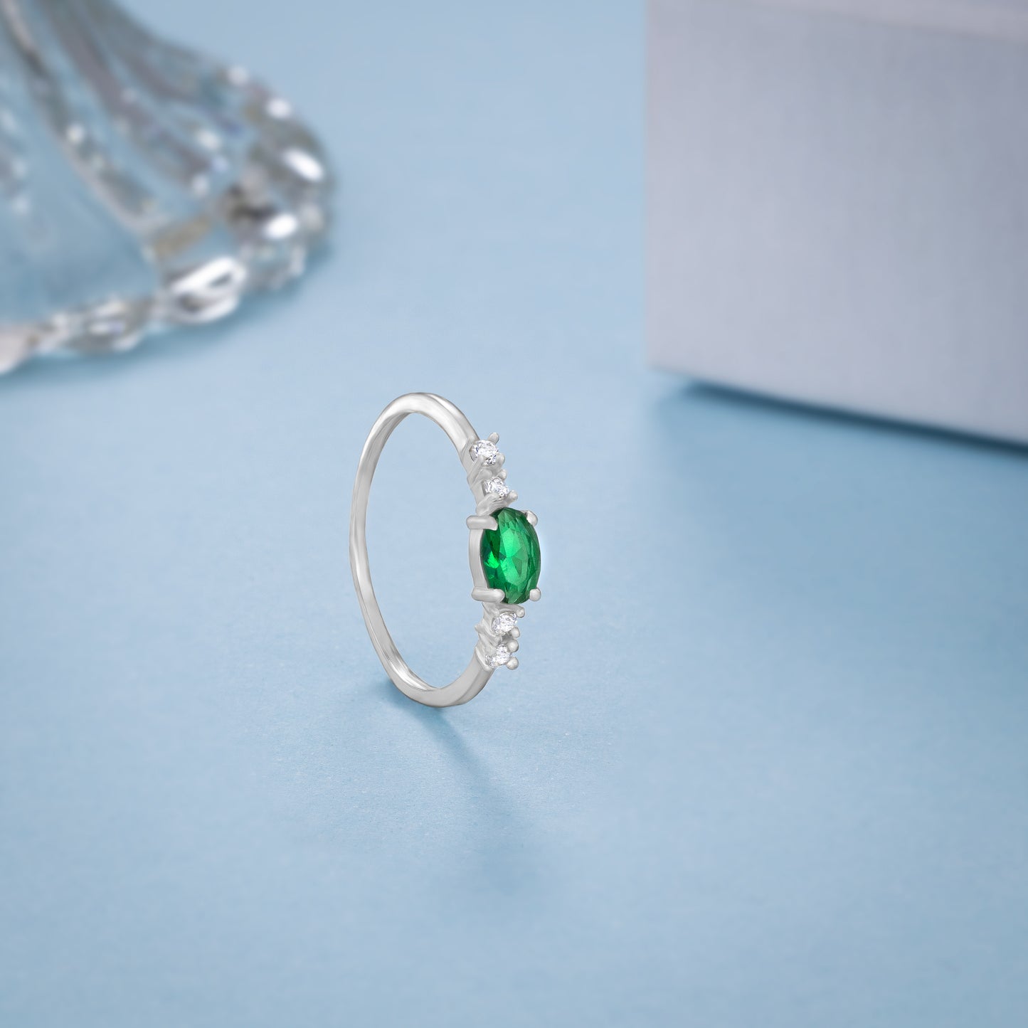 silver ring with a sapphire and green diamonds