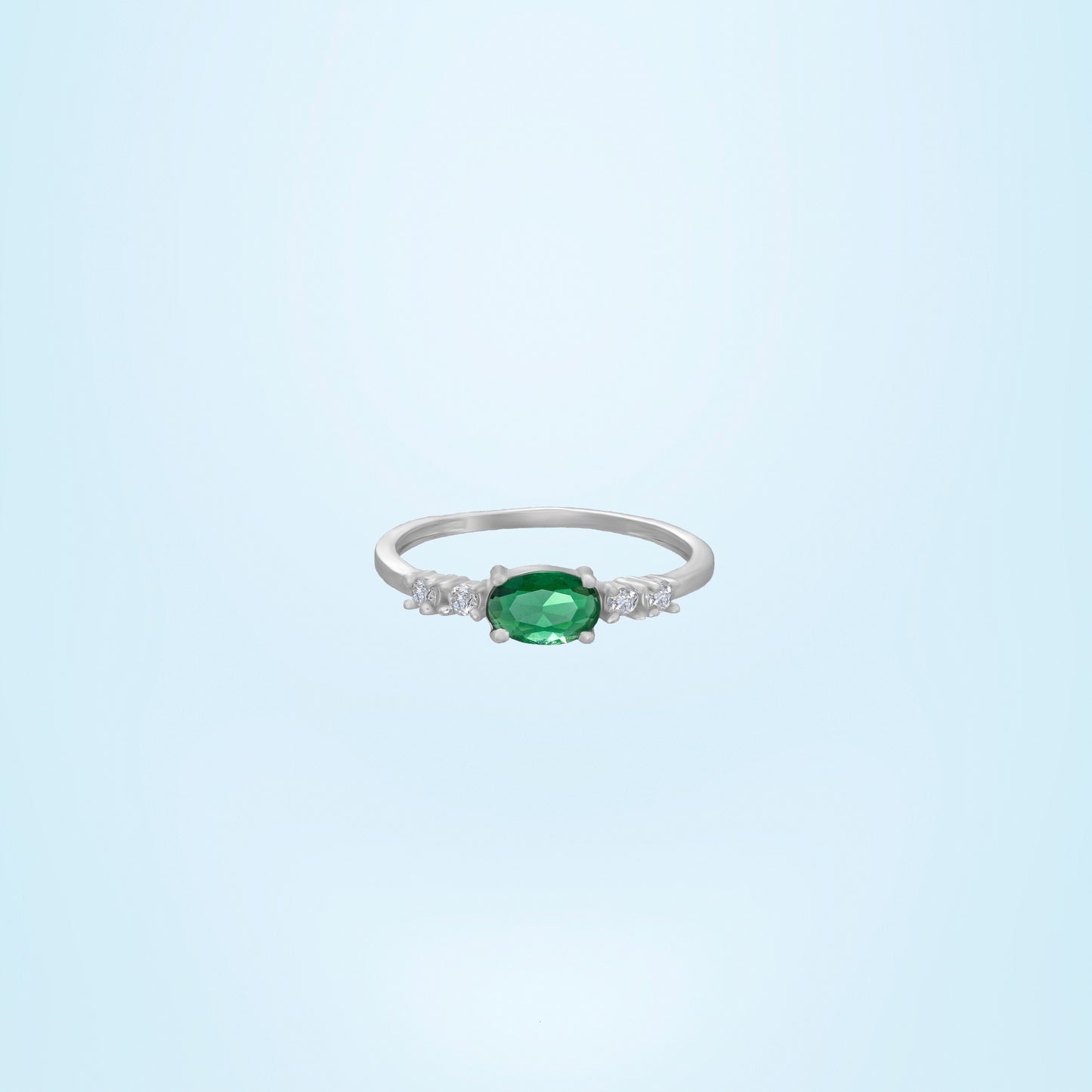 silver ring with a sapphire and green diamonds