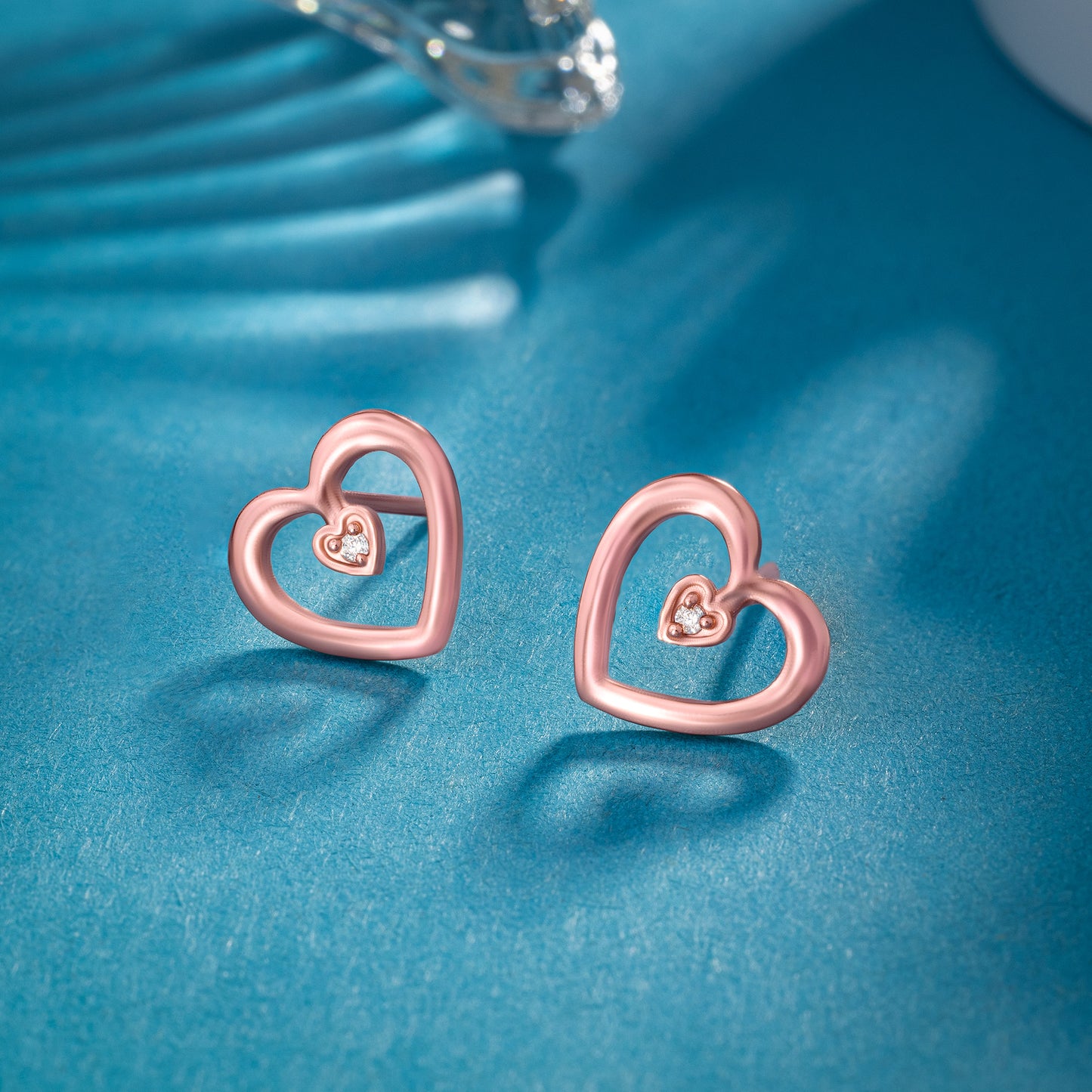 pair of rose gold heart earrings with diamond