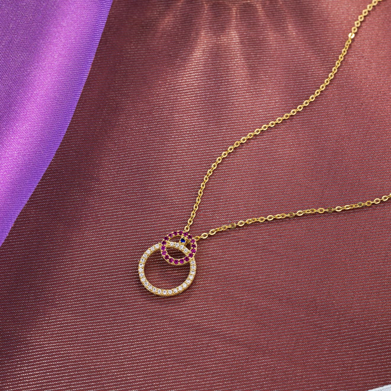 golden necklace with a diamond and ruby stone