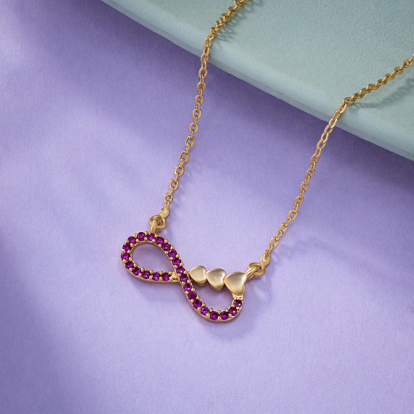 shine bright with this stunning golden necklace featuring a red infinity