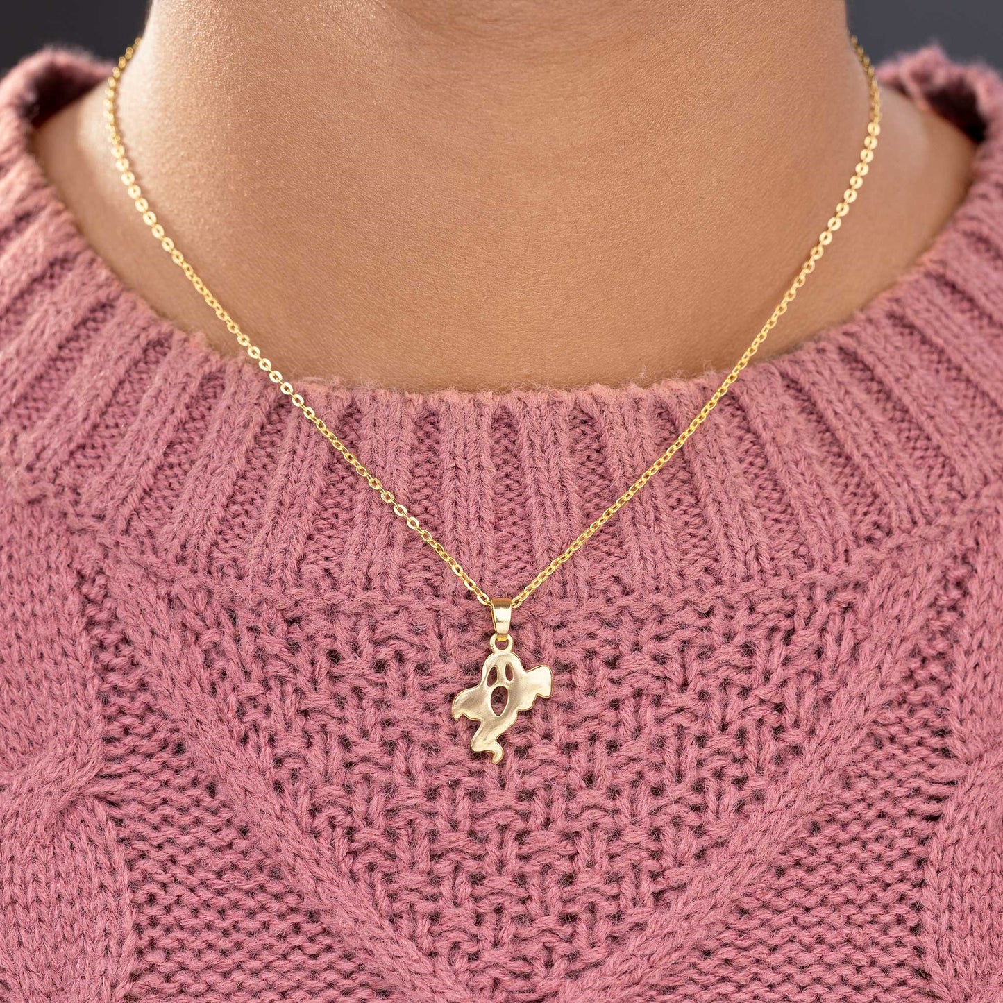 golden necklace with a small ghost  on it