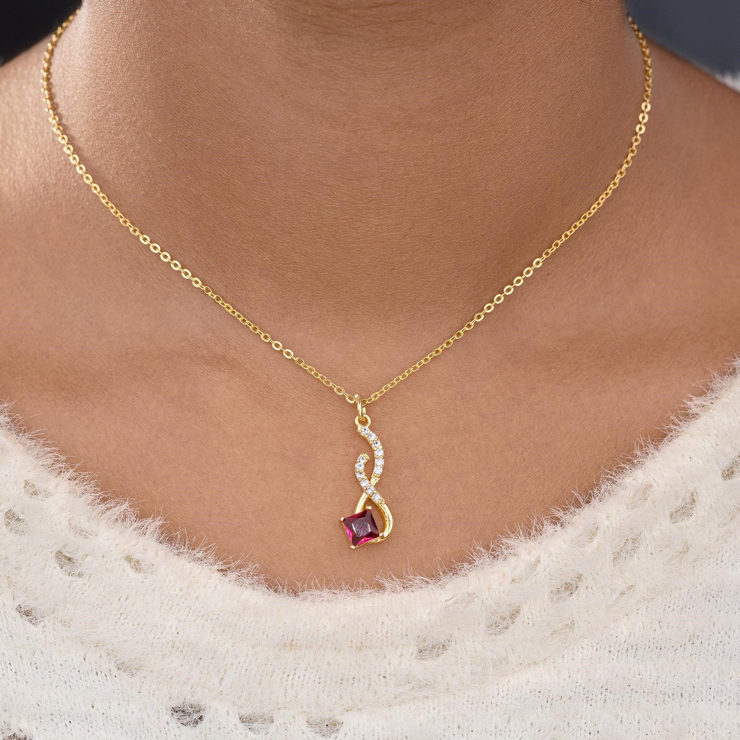 golden necklace with a red stone pendant