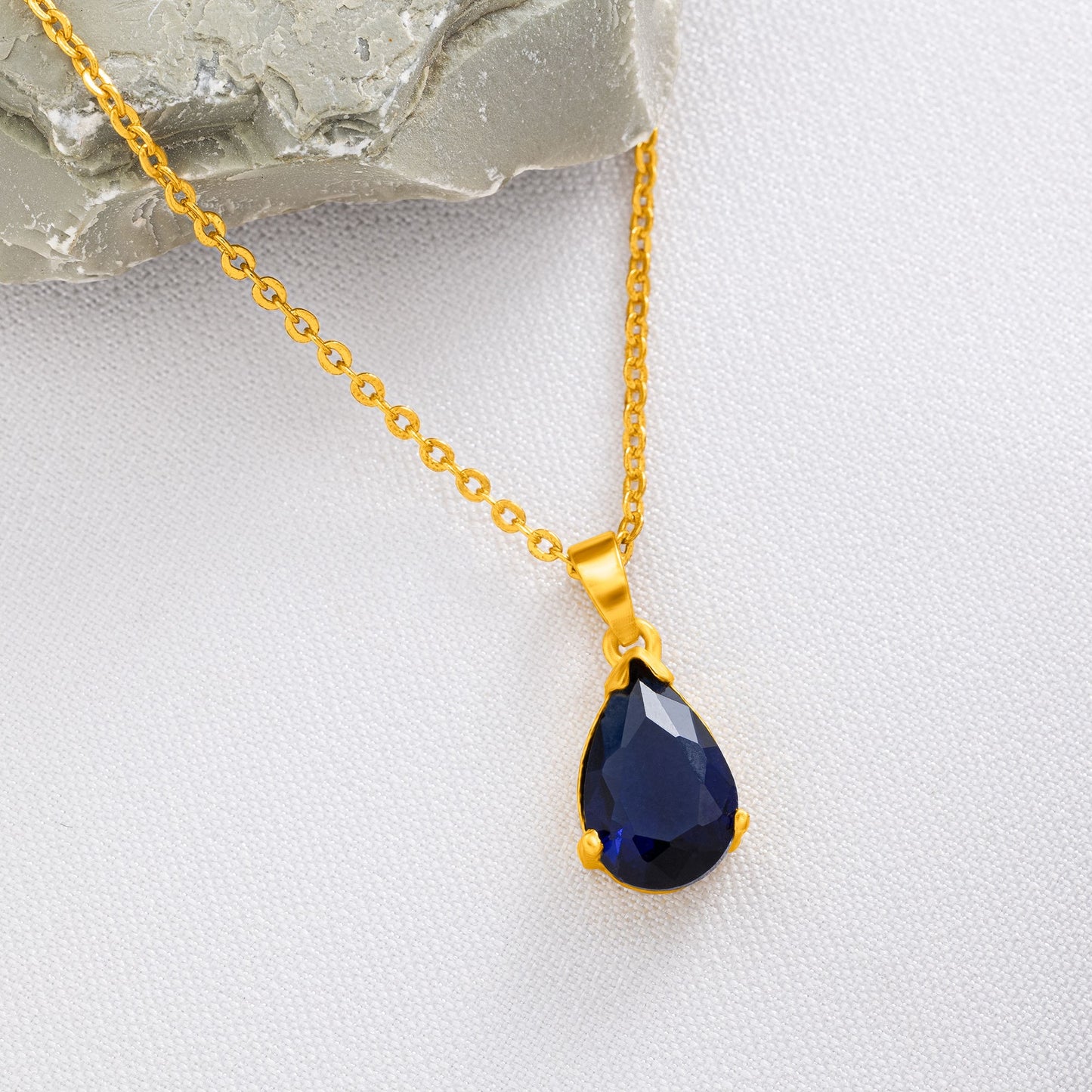 golden necklace with a small blue stone