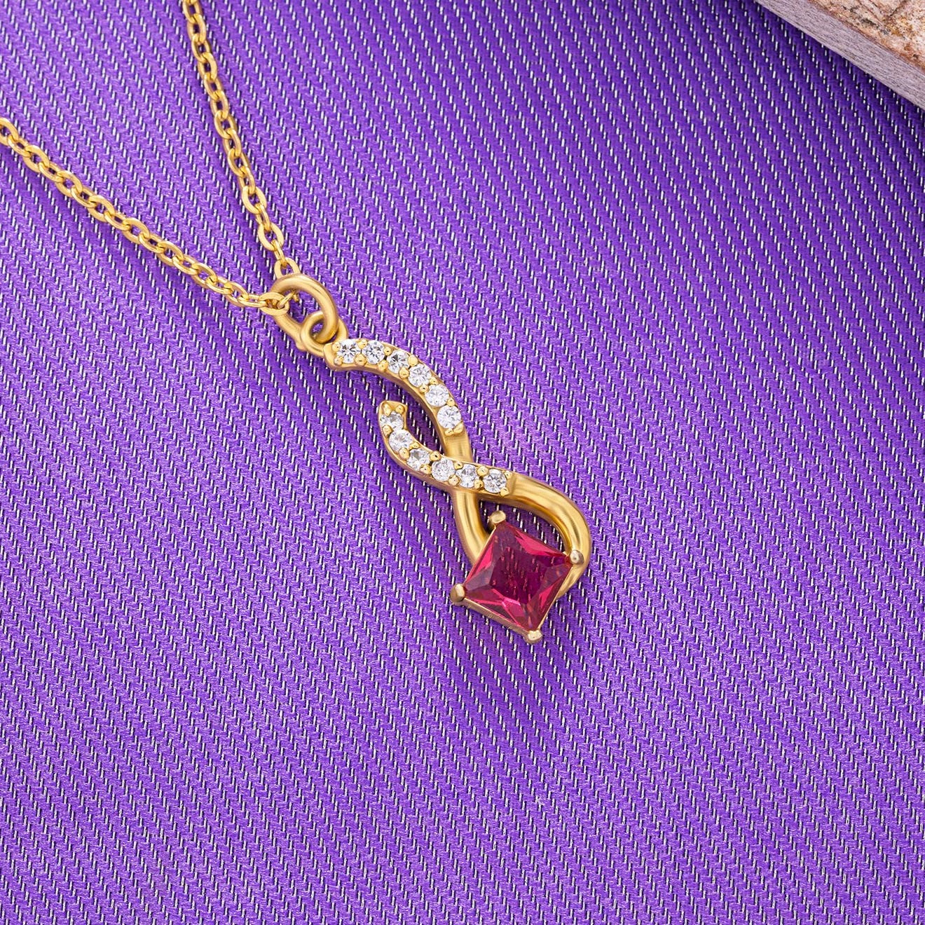 golden necklace with a red stone pendant