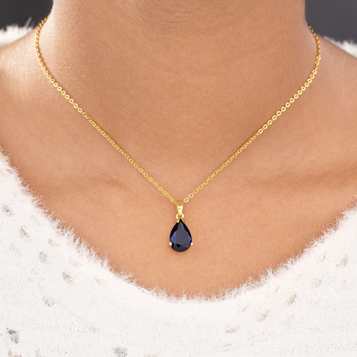 golden necklace with a small blue stone