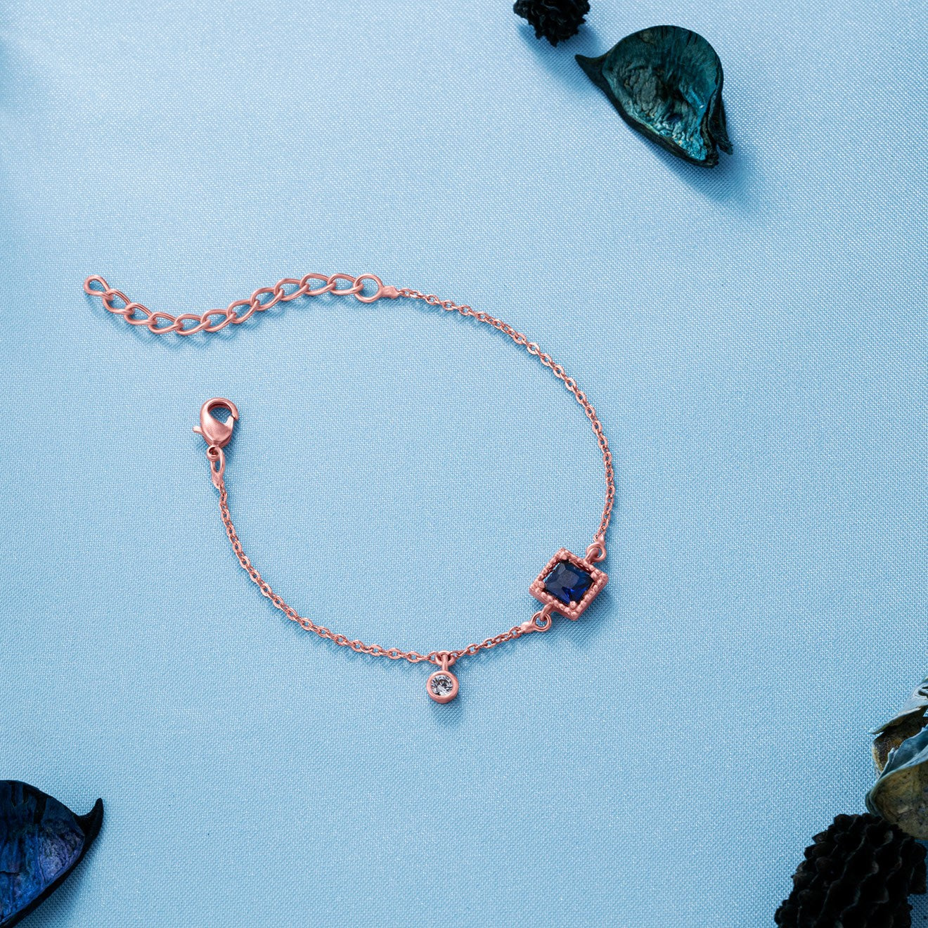 rose gold bracelet with a blue stone and hanging stud