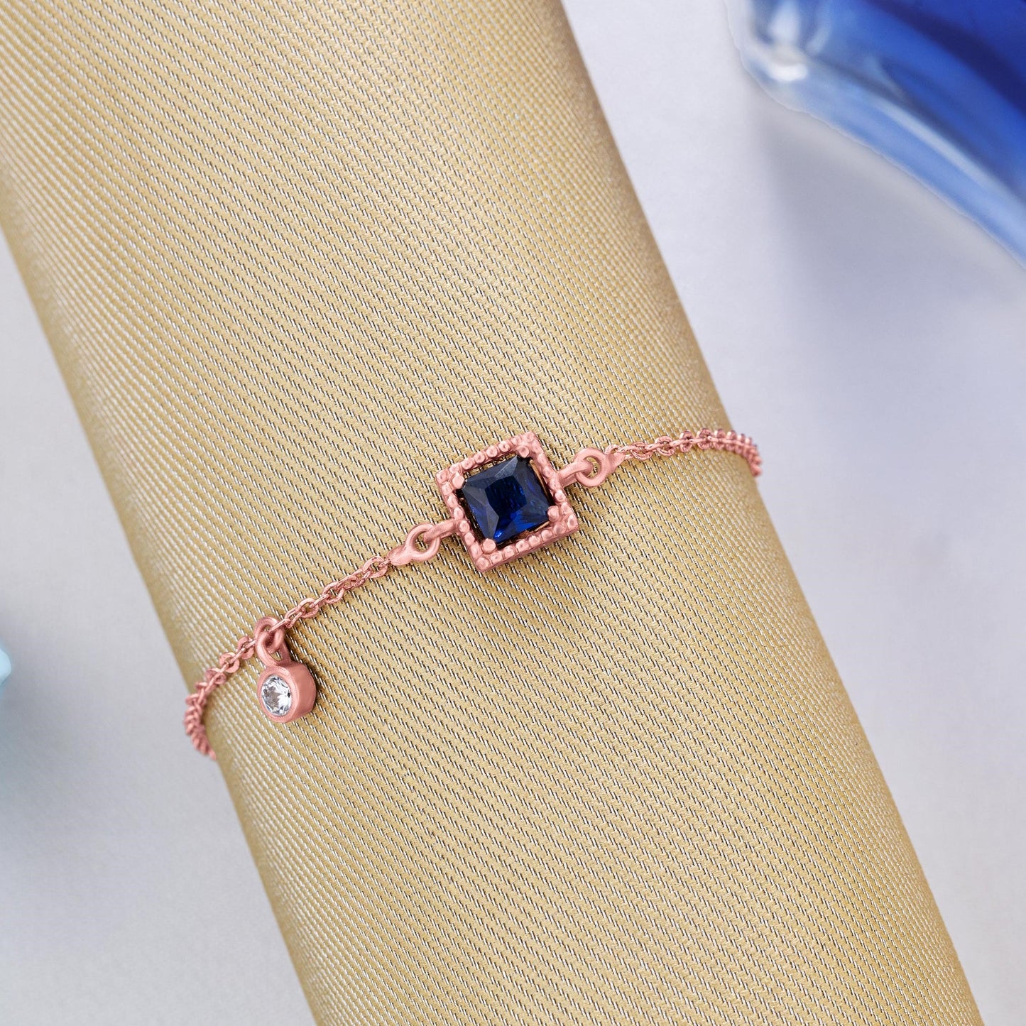 rose gold bracelet with a blue stone and hanging stud