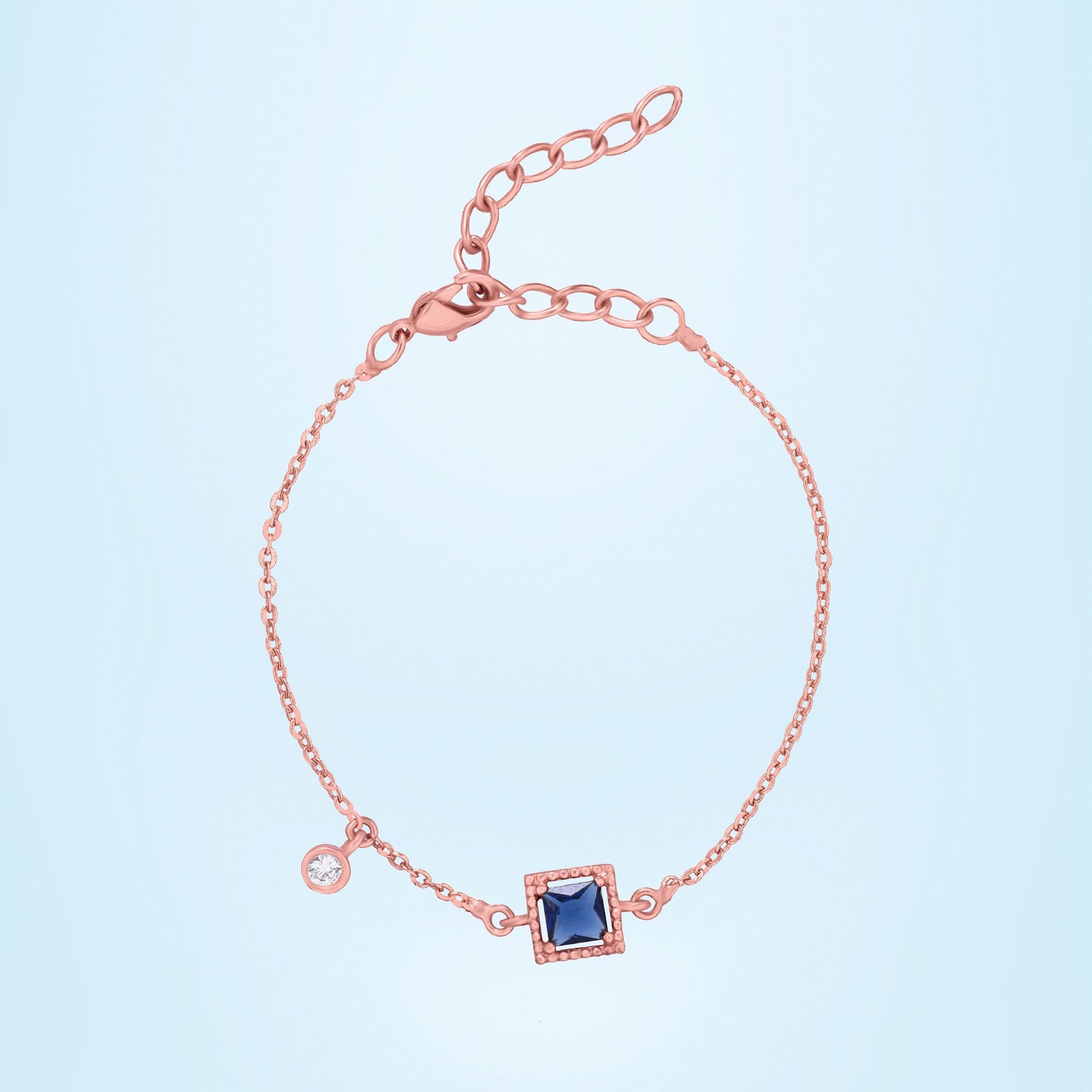 rose gold bracelet with a blue stone and hanging stud