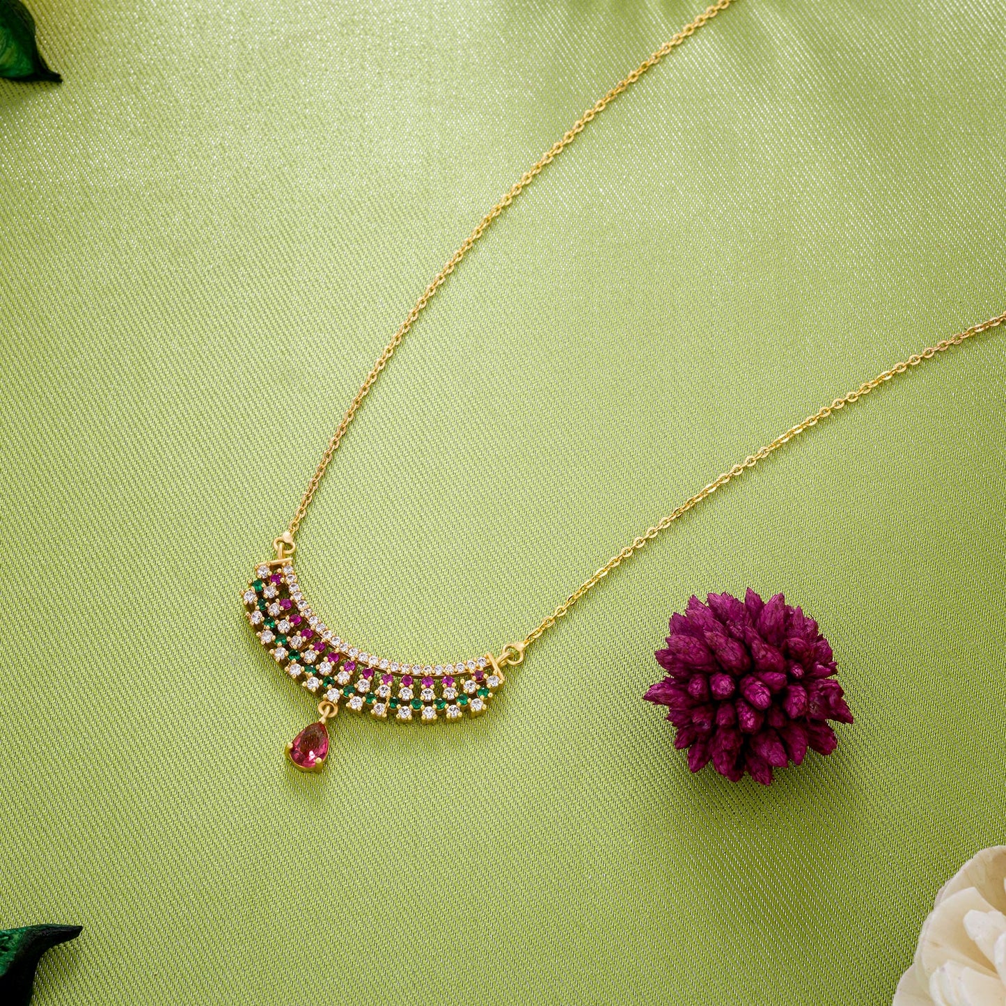 golden necklace with a ruby and emerald stone