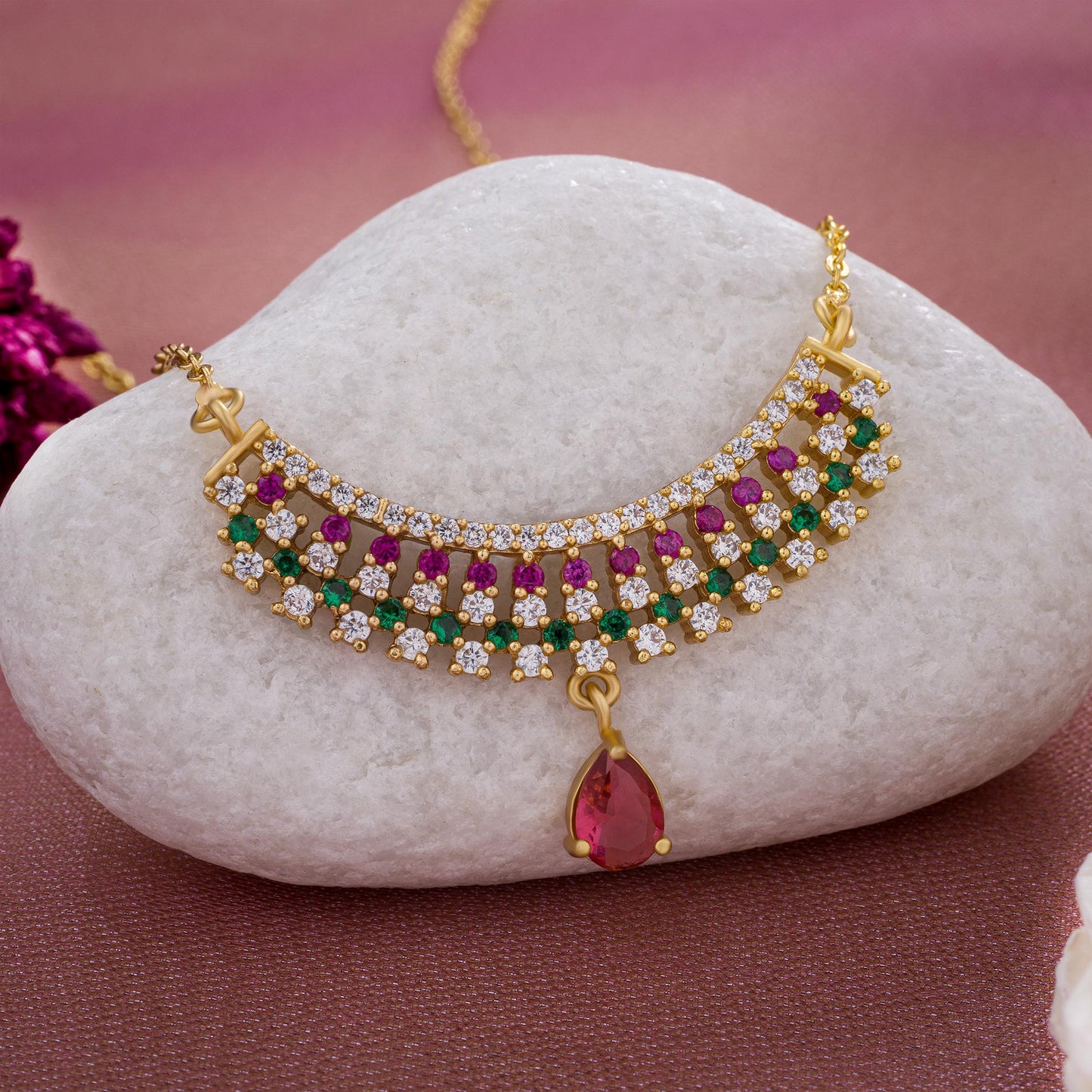 golden necklace with a ruby and emerald stone