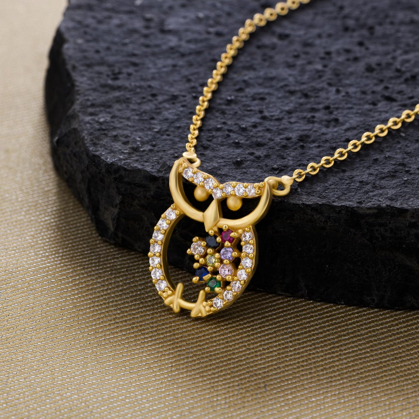 golden necklace with a diamond and emerald stone