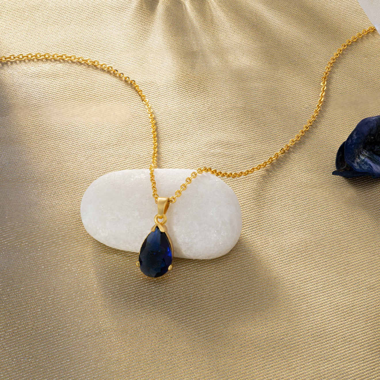 golden necklace with a small blue stone