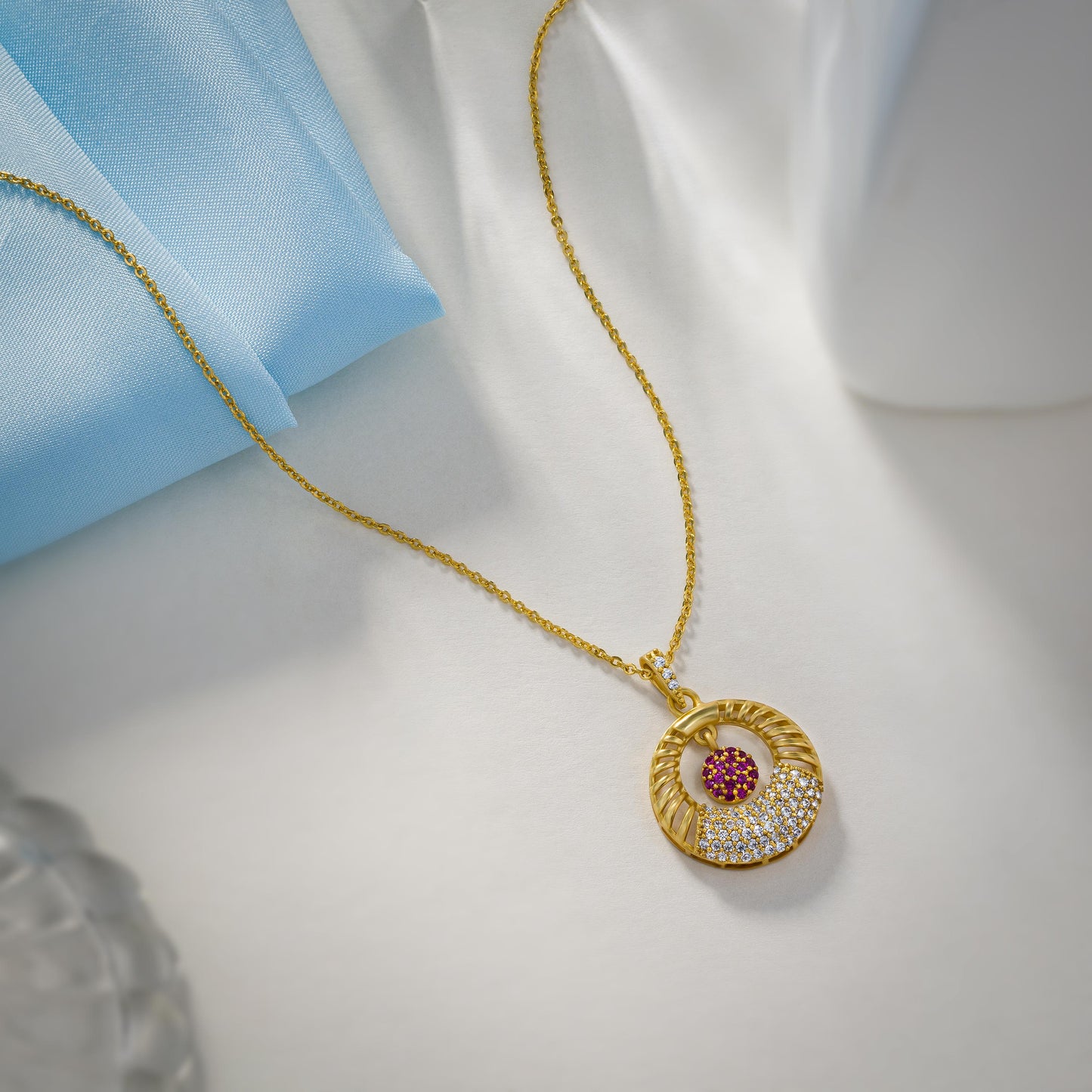 golden necklace with a pink stone and a diamond pendant