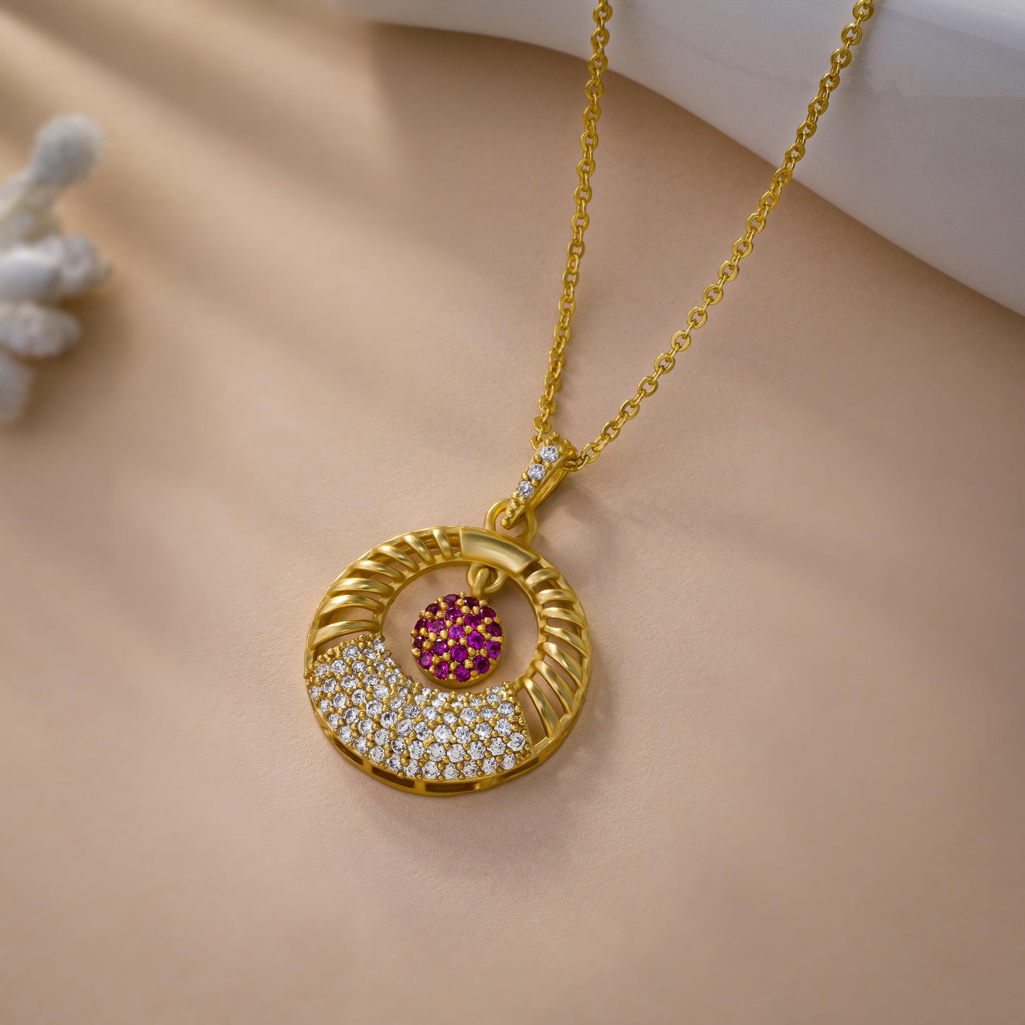 golden necklace with a pink stone and a diamond pendant